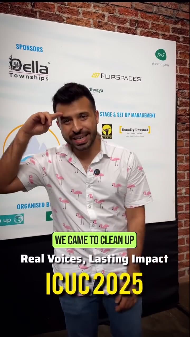 Sahir Doshi raising a hand in salute to camera in front of the ICUC 2.0 sponsor backdrop