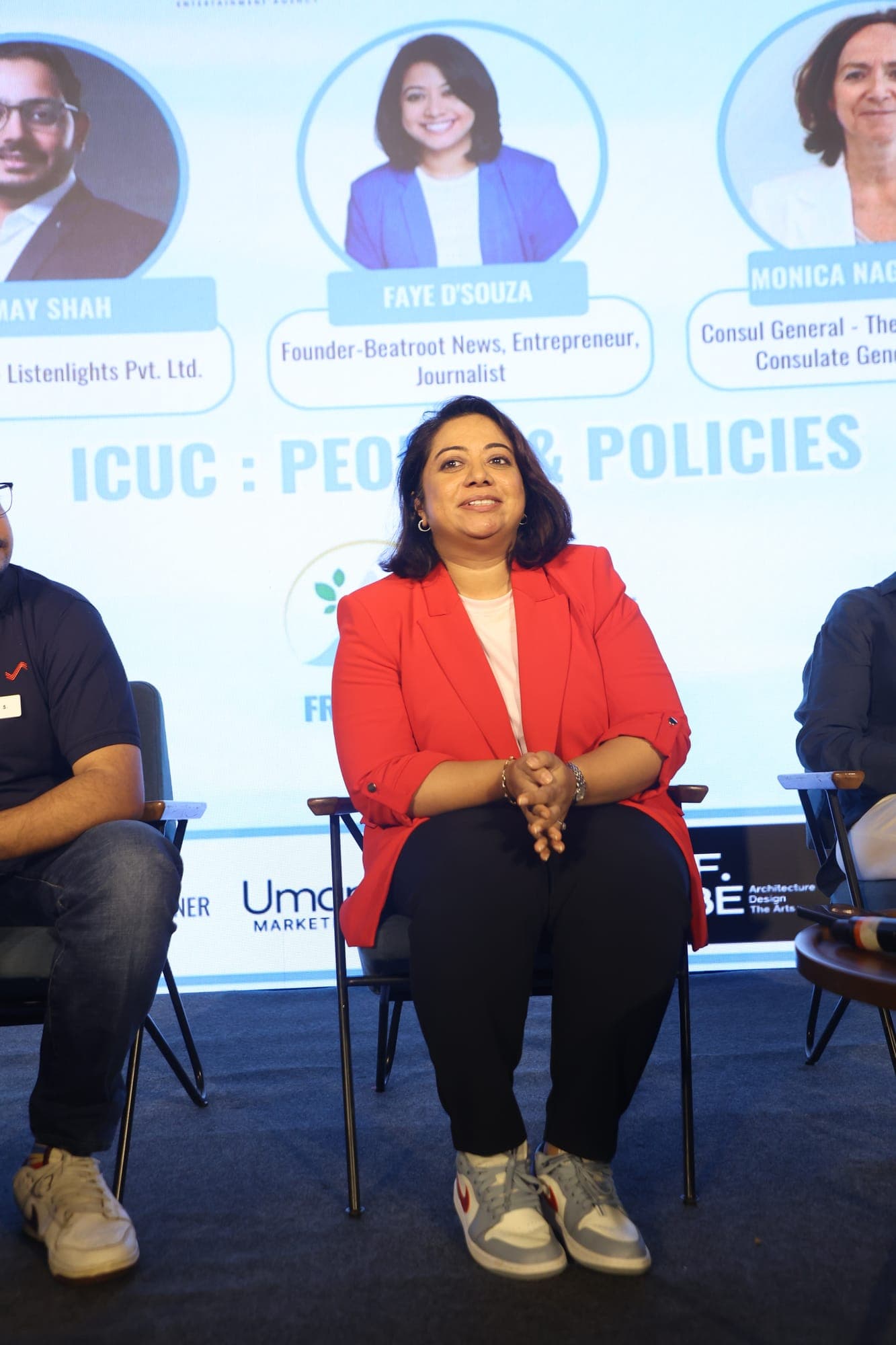 A panellist seated on stage beneath a screen reading People and Policies