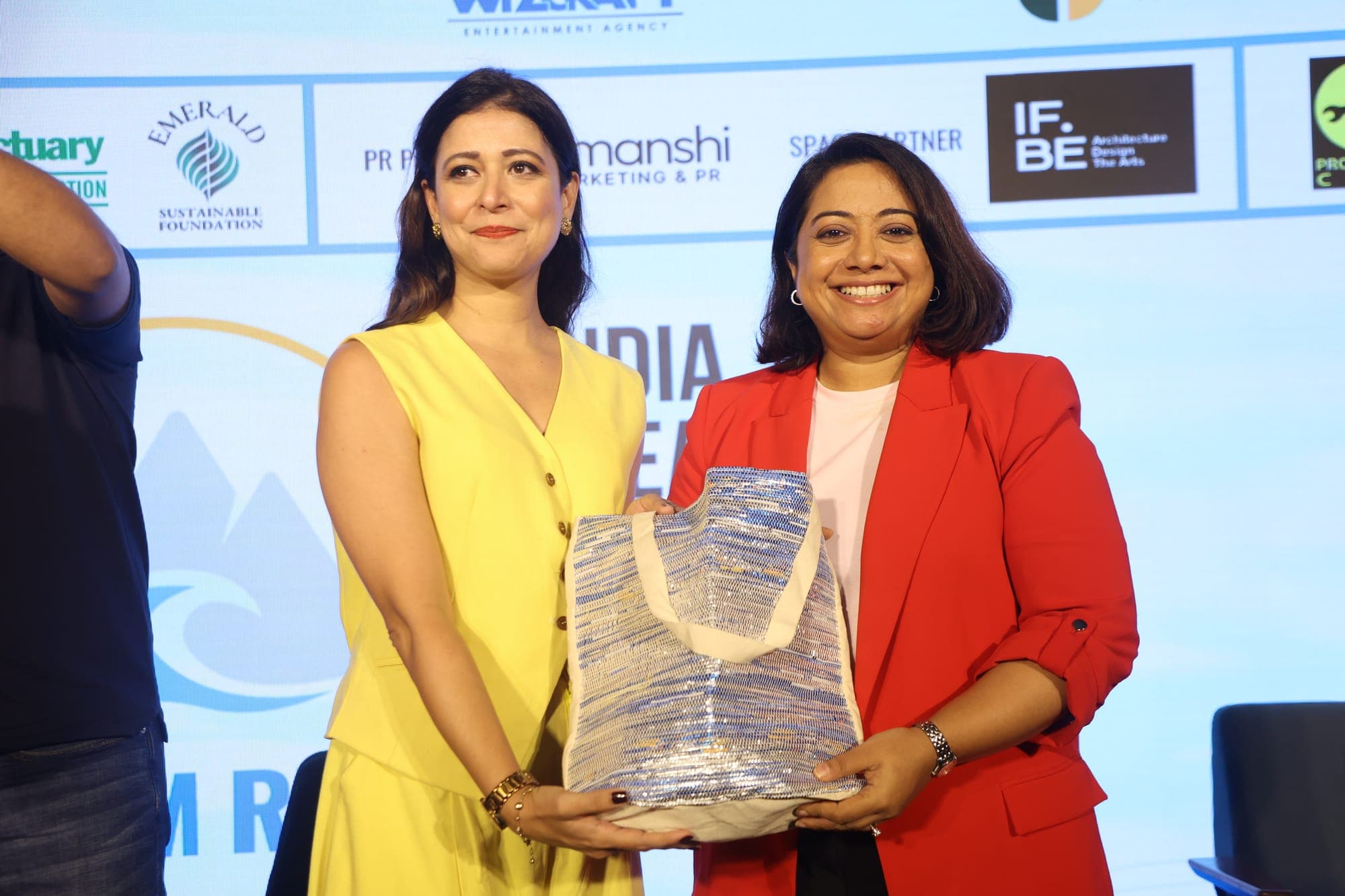 Two delegates on stage, one holding a framed award