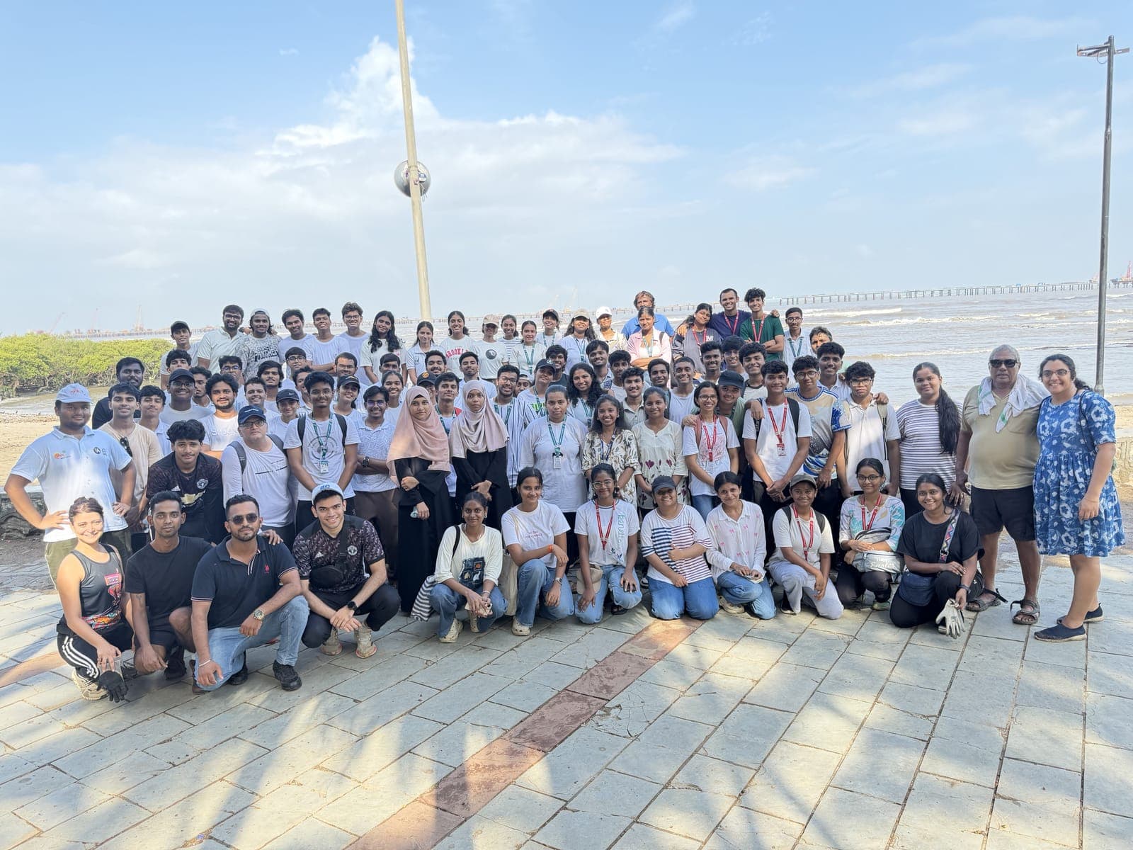 Carter Clean Up volunteers gathered for a group photo along Carter Road, Bandra, with the mangroves and sea behind them