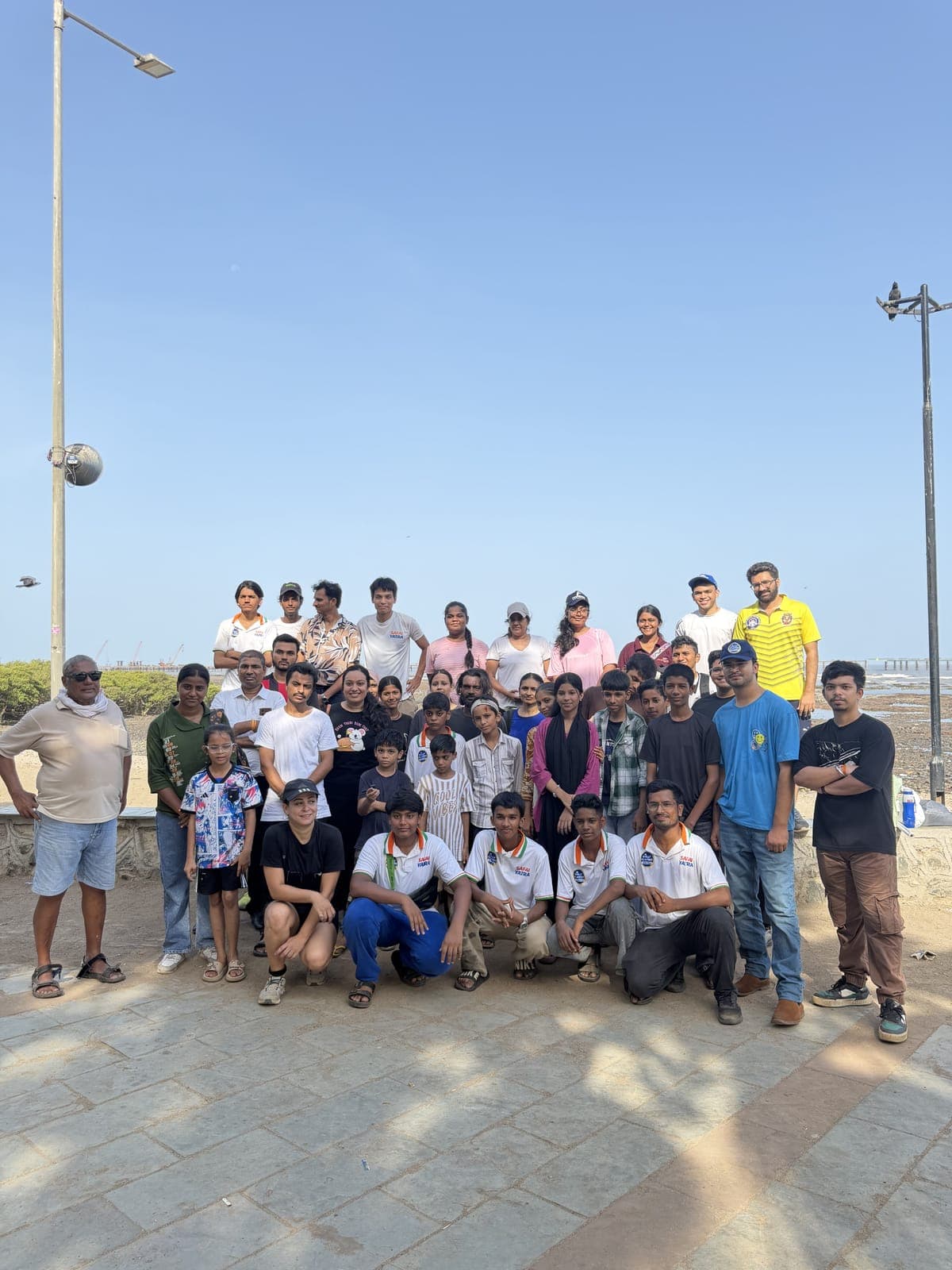 A Carter Clean Up group photo including volunteers wearing Safai Yatra t-shirts, on the promenade beside the sea